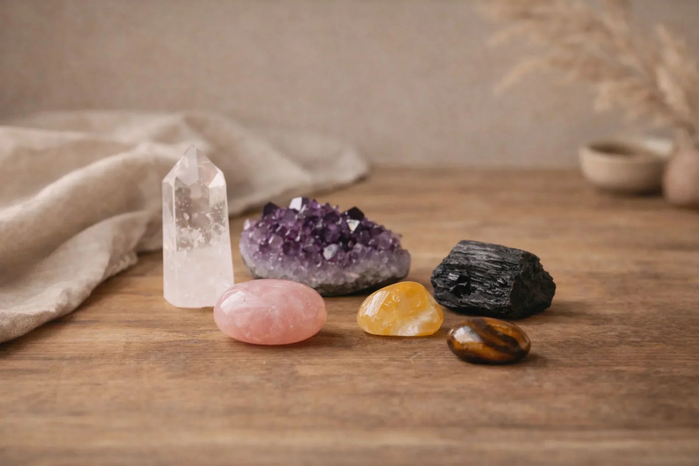 Natural crystal collection for beginners including clear quartz, amethyst, rose quartz, citrine and black tourmaline arranged on neutral bohemian surface